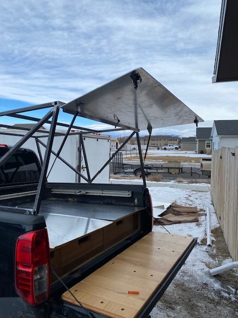 Custom steel truck-bed topper with a gull-wing side panel raised